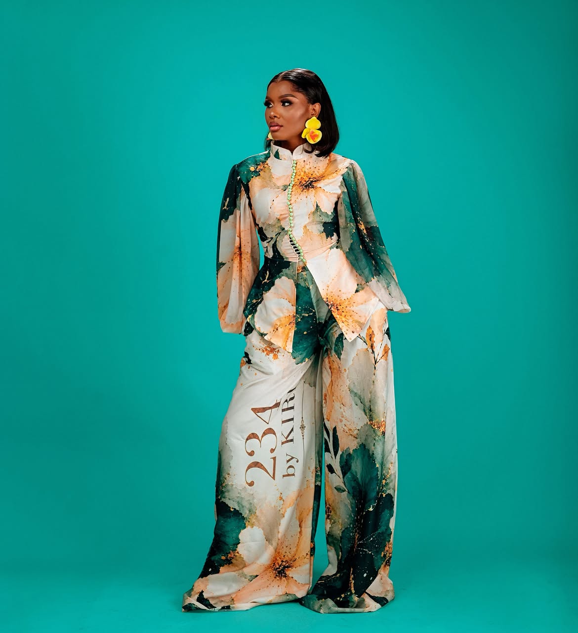 Model wearing a floral trouser set against a teal background