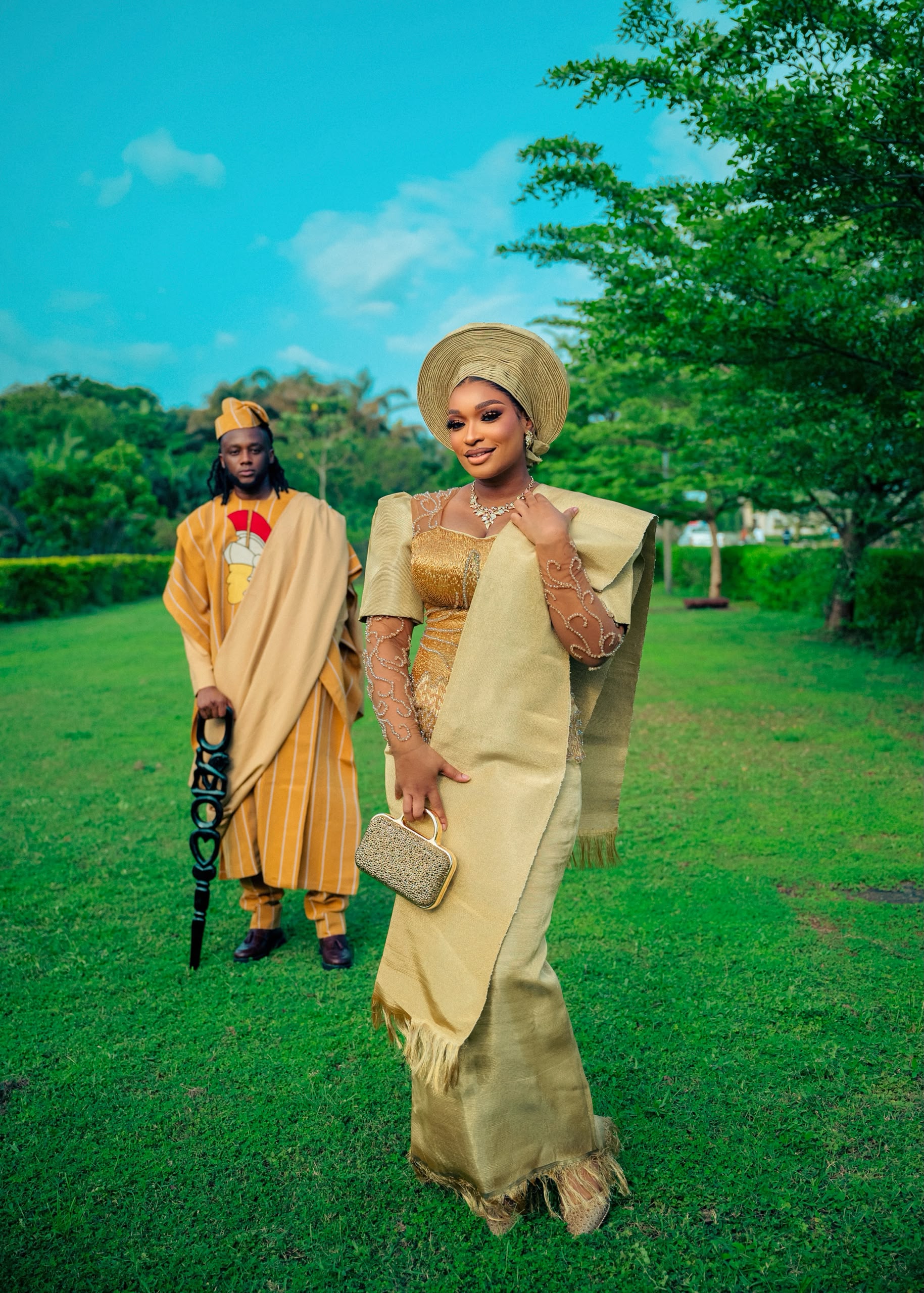 Bride in golden aso oke with gele beside her groom in mustard agbada