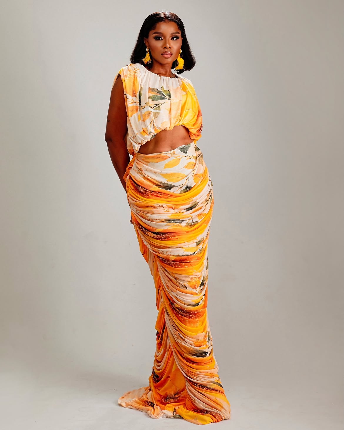 Model wearing an orange and gold draped two piece