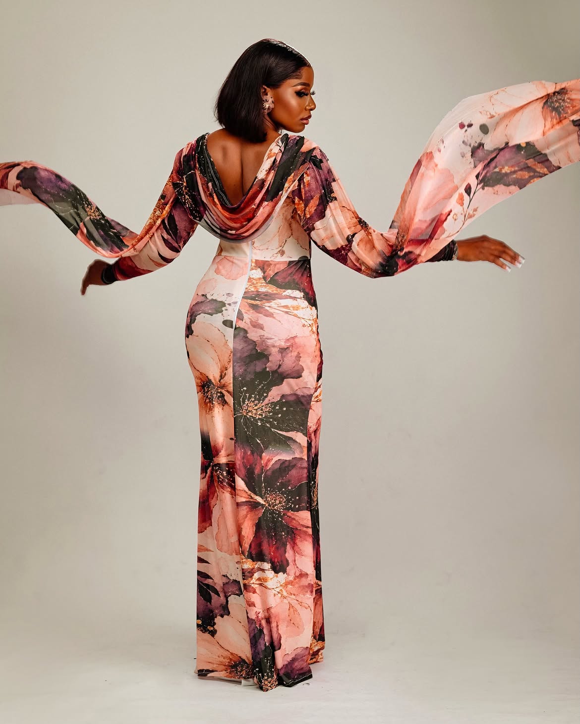 Model showing the back of a flowing pink floral gown