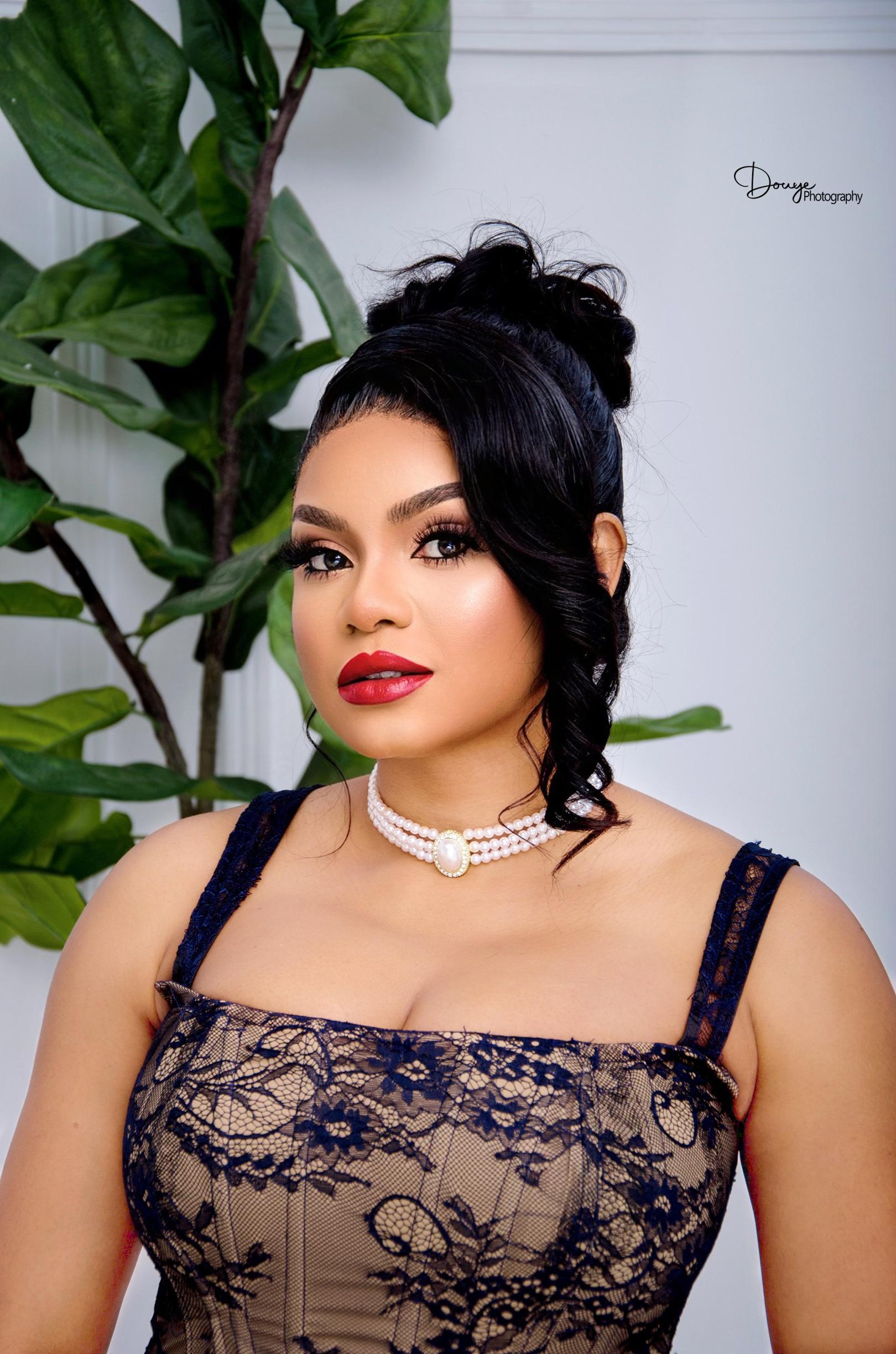 Tessy Kiri Bibowei in a navy lace top with a red lip and a pearl choker